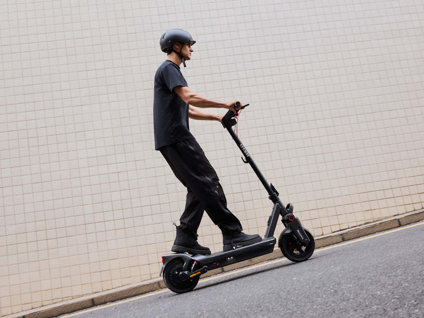 segway ninebot max g3 electric scooter lifestyle guy riding grid wall